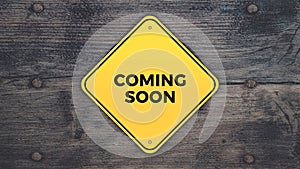 Yellow road sign saying coming soon graphic design on grey wooden digital background