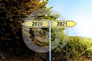 Yellow road signs in opposite directions with text 2020 and 2021, pointing to a brighter future, New Year concept, copy space