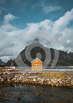 Yellow rorbu houses of Sakrisoy fishing village on a cloudy day with mountains in the background. Lofoten islands