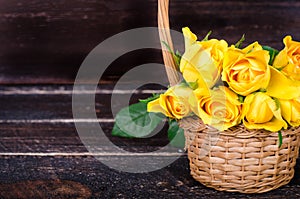 Yellow roses in a basket, vintage book on wooden background. Free space for your text