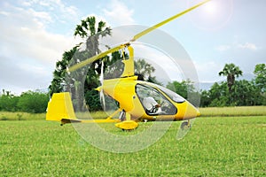 Yellow rotorcraft on grass near trees outdoors