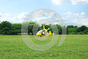 Yellow rotorcraft on grass near trees outdoors