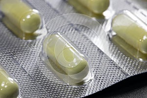 Yellow round pills in a package on a black background