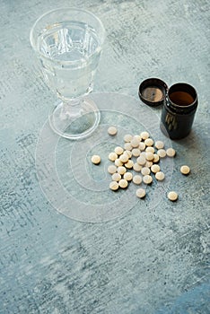 Yellow round tablets pills vitamins, plastic bottle and glass cup