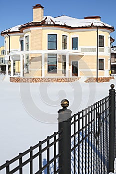 Yellow roundish two-storey new cottage and fence