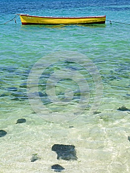 Yellow rowing boat floating on transparent blue Indian Ocean Mauritius