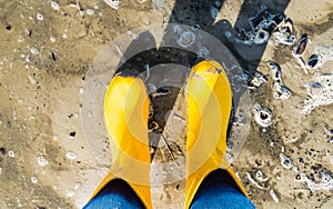 With yellow Rubber Boots on the Beach