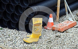 Yellow rubber boots and plastic tubes in road construction