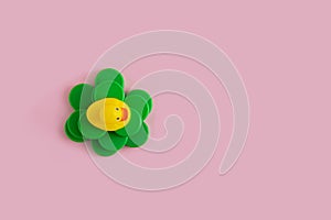Yellow rubber duck on a green plastic waste pollution island  on a pink pastel background. Polluted environments. Flat lay
