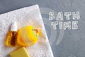 Yellow rubber duck toy with soap, shampoo and towel in the bathroom with the word bath time. Baby or children bathing