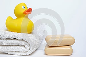 Yellow rubber duckling on white terry towel and two pieces soap