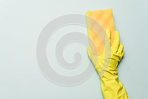 Yellow rubber glove is holding sponge on the bluebackground. yellow rubber glove is cleaning with sponge