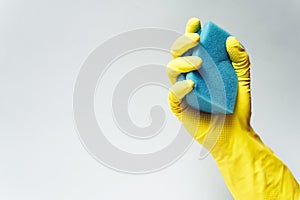 Yellow rubber glove is holding sponge on the white background. Copy space