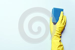 Yellow rubber glove is holding sponge on the white background. yellow rubber glove is cleaning with sponge