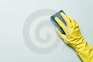 yellow rubber glove is holding sponge on the white background. yellow rubber glove is cleaning with sponge