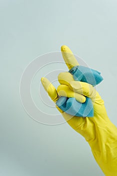yellow rubber glove is holding sponge on the white background. yellow rubber glove is showing rock sign