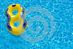 Yellow rubber ring floating on blue water