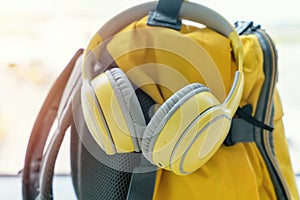 Yellow ruksak with cap and headphones in airport. Travel concept. Travel touristic concept. travel light. Take music or book on a
