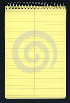 Yellow ruled spiral notepad over black photo