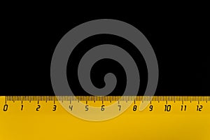 Yellow ruler on a black background 12 centimeters