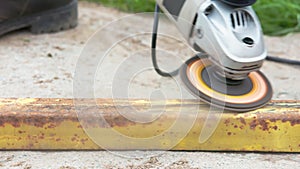 Yellow rusted square steel pipe is being cleaned with angle grinder and flap disc