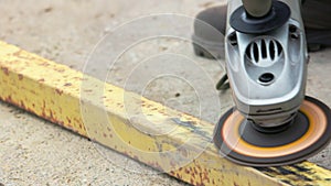 yellow rusted square steel pipe is being cleaned with angle grinder and flap disc