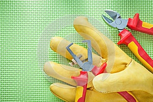 Yellow safety gloves insulation strippers nippers on green backg