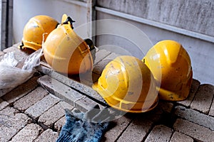 Yellow safety hard hats laying on a pile of bricks in a building construction site