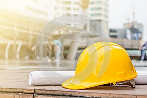 The yellow safety helmet and the blueprint at construction site with crane background