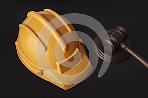 Yellow safety helmet and Judge Gavel on black background. Construction law