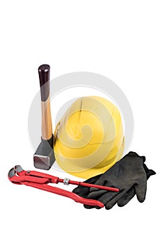 Yellow safety helmet with a sledgehammer with wooden handle, working gloves and adjustable plumbers wrench isolated on a white bac