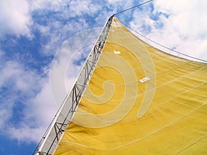 Yellow sail yacht on sky background