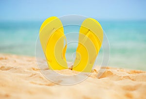 Yellow sandal flip flop on the white sand beach with blue sea and sky background in summer vacations copy space