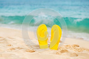 Yellow sandal flip flop on the white sand beach with blue sea and sky background in summer vacations copy space