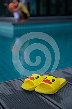Yellow sandals duckling on table beside the swimming pool