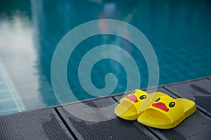 Yellow sandals duckling on table beside the swimming pool