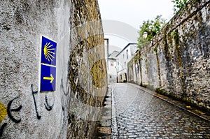 Yellow scallop shell and arrow on a wall signing the way to santiago de compostela in Galicia