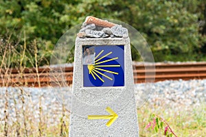 Yellow scallop shell, touristic symbol of the Camino de Santiago showing direction on Camino Norte in Spain.Column with rocks