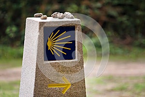 Yellow scallop shell, touristic symbol of the Camino de Santiago showing direction on Camino Norte in Spain. Column signing the