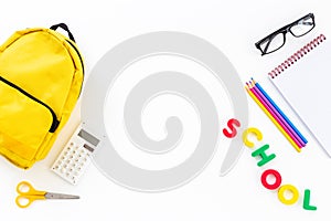 Yellow school backpack with colorful school stationery
