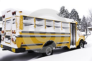 Yellow school bus covered with snow parked in a residential neighborhood on a snow day