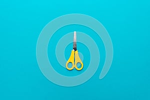 Yellow scissors on the blue background