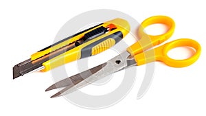 Yellow scissors and cutter knife isolated on white background
