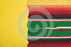 Yellow scrap paper on colorful serape. Empty template for text