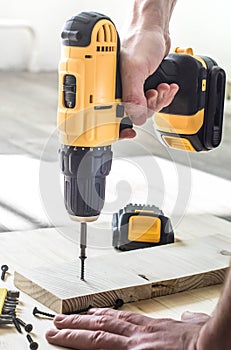 yellow screwdriver on a wooden table, screws, a set of bits.