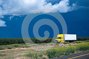 Yellow semi truck going thrue green bushes and trees