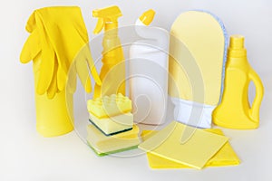 Yellow set of products for washing and cleaning. Rubber gloves, chemical bottles, sponges and rags.