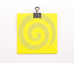 yellow sheet of paper with black paper clip on a white background