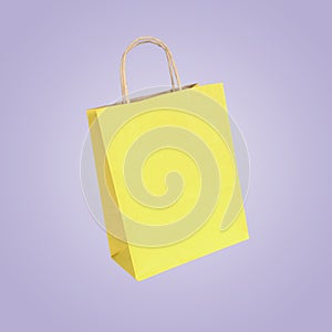 Yellow shopping bag in air on lilac background