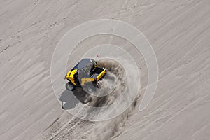 Yellow side by side buggy racing by in the sand dunes